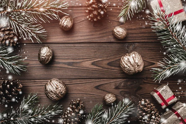 Fundo de madeira marrom. Ramos de abeto, cones de abeto e nozes decorativas. presentes para o Natal. Cartão de Natal e Ano Novo. Flocos de neve . — Fotografia de Stock