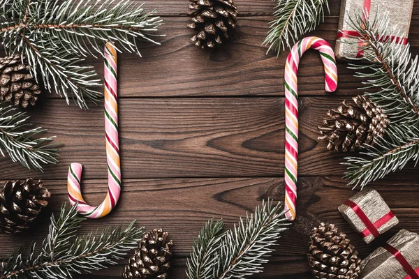 Kahverengi ahşap arka plan. Çam dalları, dekoratif koniler. Renkli şekerler. Xmas hediyesi. Noel tebrik kartı ve yeni yıl. Şık. Noel ve mutlu yeni yıl kompozisyon.