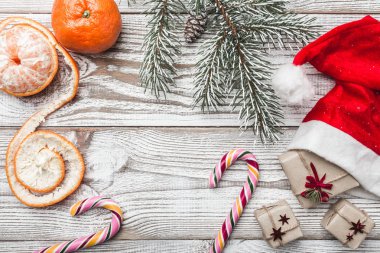 Ahşap arka plan. Beyaz. Kış kartı. Onun Noel Baba'nın şapka. Hediyeler. Renkli şekerler. Çam ağacı. Mandalina.