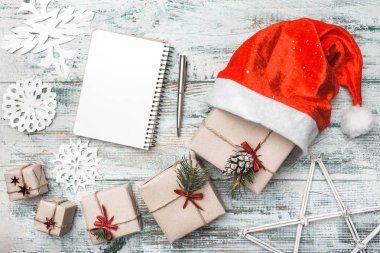 En iyi görünüm güzel Noel hediyeleri üzerinde beyaz hediye kağıt, Noel ağacı süslemeleri Noel Baba'nın şapkalı parlak yıldız ahşap zemin üzerine sarılı. Yeni yıl, tatil ve kutlama kavramı