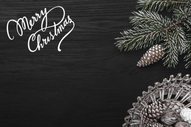 Siyah bir arka plan, koni ve dekoratif objeler ile bir köknar ağacı üzerinde. Noel mesajı alan. Üstten Görünüm.