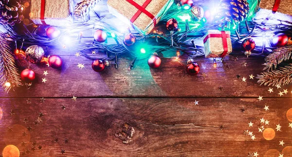 Wooden background With colorful lights, toys and gifts arranged in the top, with light bulbs. Horizontally. With congratulatory message space. Top view.