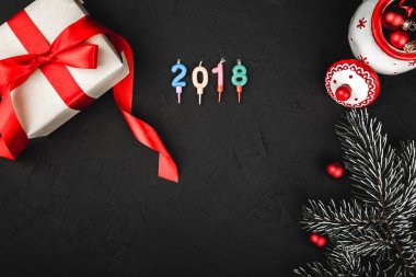 Siyah arka plan, 2018 sayı mum ile kırmızı kurdele, mevcut üst üstten görünüm, el yapımı Noel oyuncak ve bir taş üzerinde evergreen şube
