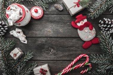 Noel tebrik kartı ahşap arka plan, köknar twigs, koniler, bir kardan adam, kış tatili, tatlılar, şeker ve xmas hediye ile mesaj için alan.