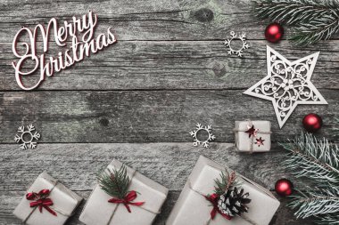Üst, üst, görüntülemek üzerinden yukarıda beyaz kış figürinler, herdem yeşil dal, kırmızı oyuncak, hediyeler ve yazma, tebrik metin için yer ile gri arka plan üzerinde mutlu Noeller yazıt