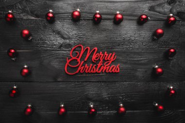 Üst, üst, görüntülemek üzerinden yukarıda, herdem yeşil kırmızı oyuncak ve hafif kırmızı mutlu Noeller yazıt, siyah ahşap arka plan, metin yazma, tebrik için yer ile.
