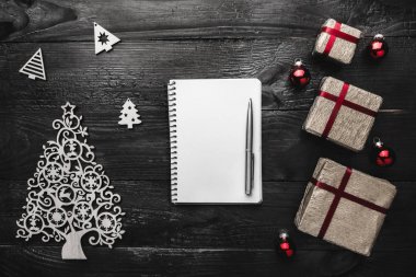 Üst, üst, görüntüleme üzerinden yukarıda kış figürinler, not defteri ve kalem siyah arka plan üzerine yazma, tebrik metin için yer ile Noel hediyeleri.