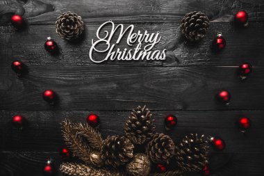 Üst, üst, görüntülemek üzerinden yukarıda, herdem yeşil çam ağaçları, kırmızı oyuncak ve yazma, tebrik metin için yer ile siyah ahşap zemin üzerine beyaz Merry Christmas yazıt.