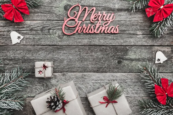 Üst, üst, görüntülemek üzerinden yukarıda beyaz kış figürinler, herdem yeşil dal, kırmızı yay, hediyeler ve yazma, tebrik metin için yer ile gri arka plan üzerinde mutlu Noeller yazıt