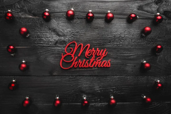 Üst, üst, görüntülemek üzerinden yukarıda, herdem yeşil kırmızı oyuncak ve hafif kırmızı mutlu Noeller yazıt, siyah ahşap arka plan, metin yazma, tebrik için yer ile.