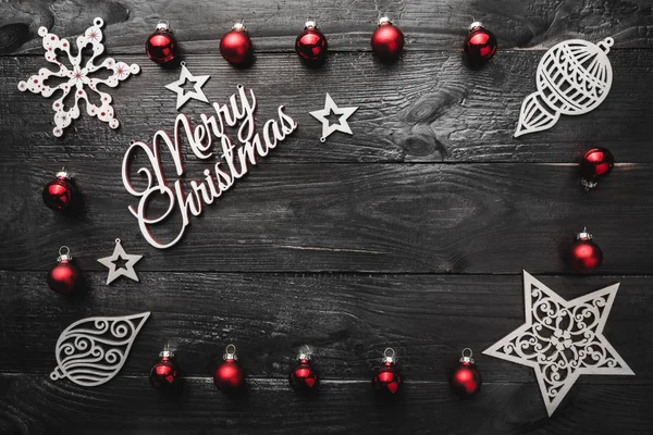 Üst, üst, görüntülemek üzerinden yukarıda, ahşap kış figürinler, kırmızı oyuncak ve yazma, tebrik metin için yer ile siyah arka plan üzerinde beyaz Merry Christmas yazıt.