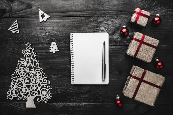 Üst, üst, görüntüleme üzerinden yukarıda kış figürinler, not defteri ve kalem siyah arka plan üzerine yazma, tebrik metin için yer ile Noel hediyeleri.