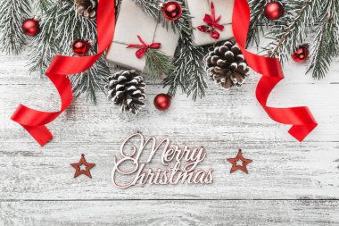 Yukarıdan görünüm, üst, köknar dalı pines, mevcut kutuları, şerit, kırmızı ağaç Küre, el yapımı ağaç oyuncaklar ve Merry Christmas yazıt, tebrik kartı ile bir beyaz ahşap tahta zemin üzerine