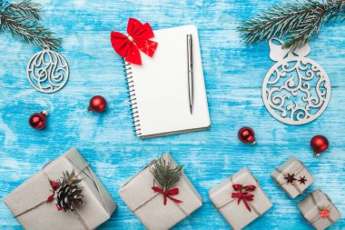 Not defteri ve kalem ile yer metin dilek Noel kompozisyon ahşap evergreen oyuncak Küre ve mevcut kutuları, köknar dalı olarak için yukarıdaki mavi, ahşap arka plan üzerinde Noel tebrik kartı göster