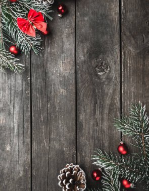 Dikey Noel Tema çam dalları, kırmızı yay ve küreler, koniler, yukarıdan izlendi rustik koyu ahşap arka plan, üst, metin için yer ile tebrik kartı