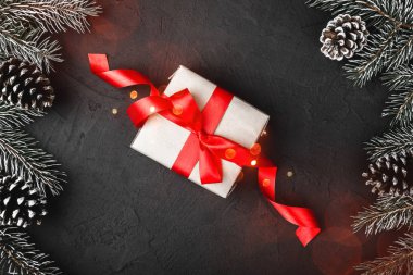 Xmas Tema bir armağan hediye kutusu ile çam dalları, evergreen pines, her bakıldığında tebrik kartı üzerinde siyah, taş zemin üzerine 