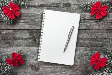 Kırmızı ok ve xmas el yapımı oyuncak ahşap gri arka plan üzerinde dört çam dalları ve kalemle metin yazma, Noel tebrik kartı için bir not defteri