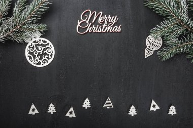 Üst, üst, görüntülemek üzerinden yukarıda, el yapımı ahşap oyuncak, yaprak dökmeyen şube ve yazma, tebrik metin için yer ile siyah arka plan üzerinde beyaz Merry Christmas yazıt.