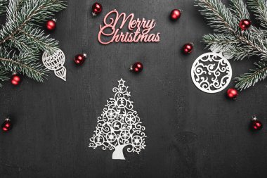 Üst, top, üzerinden yukarıda görüntülemek herdem yeşil dallar, ağaç Küre, ahşap el yapımı oyuncak ve Merry Christmas yazıt siyah arka plan, tebrik kartı üzerine beyaz.