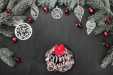 Üst, üst, görüntülemek üzerinden yukarıda, bir donut ile kırmızı yay, el yapımı ahşap oyuncak, herdem yeşil dallar, siyah arka plan, tebrik kartı üzerine kırmızı Küre.