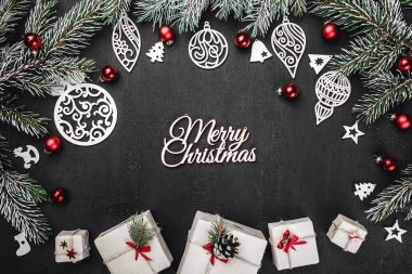 Üst, üst, profil yukarıdan, bazı yeni yıl hediyesi kutuları, el yapımı, ahşap oyuncaklar, herdem yeşil dallar, siyah arka plan, metin yazma yeri olan tebrik kartı üzerine kırmızı Küre.