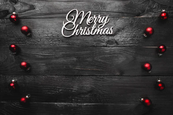 Kırmızı Küre ve neşeli Noel işareti, metin için yer ile ahşap arka plan siyah, en baştan yukarıda, tebrik kartı göster.