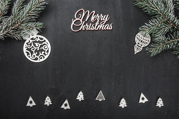 Üst, üst, görüntülemek üzerinden yukarıda, el yapımı ahşap oyuncak, yaprak dökmeyen şube ve yazma, tebrik metin için yer ile siyah arka plan üzerinde beyaz Merry Christmas yazıt.