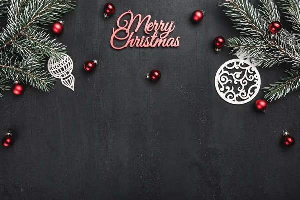 Üst, üst, görüntülemek üzerinden yukarıda, el yapımı ahşap oyuncak, yaprak dökmeyen şube ve yazma, tebrik metin için yer ile siyah arka plan üzerinde kırmızı mutlu Noeller yazıt.