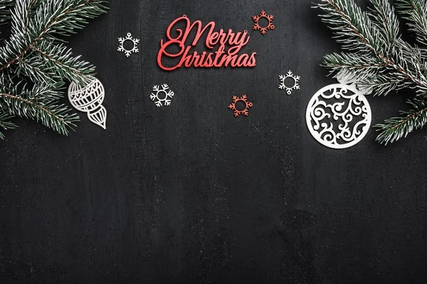 Üst, üst, görüntülemek üzerinden yukarıda, el yapımı ahşap oyuncak, yaprak dökmeyen şube ve yazma, tebrik metin için yer ile siyah arka plan üzerinde kırmızı mutlu Noeller yazıt.