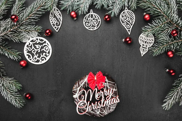 Üst, üst, görüntülemek üzerinden yukarıda, bir donut ile kırmızı yay, el yapımı ahşap oyuncak, herdem yeşil dallar, siyah arka plan, tebrik kartı üzerine kırmızı Küre.