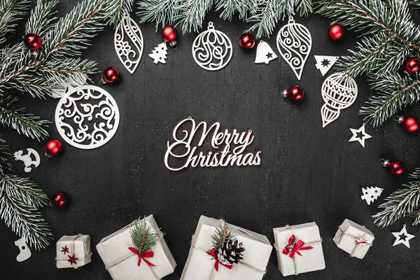 Üst, üst, profil yukarıdan, bazı yeni yıl hediyesi kutuları, el yapımı, ahşap oyuncaklar, herdem yeşil dallar, siyah arka plan, metin yazma yeri olan tebrik kartı üzerine kırmızı Küre.
