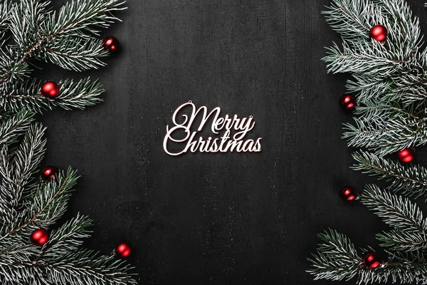 Üst, üst, görüntülemek yukarıdan, herdem yeşil dallar, ağaç Küre ve yazma, tebrik metin için yer ile siyah arka plan üzerinde beyaz Merry Christmas yazıt.