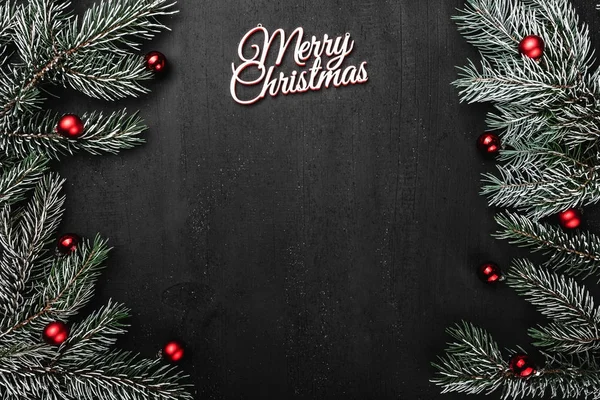 Üst, üst, görüntülemek yukarıdan, herdem yeşil dallar, ağaç Küre ve yazma, tebrik metin için yer ile siyah arka plan üzerinde beyaz Merry Christmas yazıt.