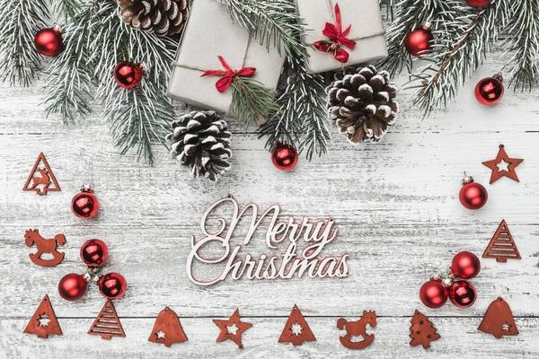 Yukarıdan görünüm, üst, köknar dalı pines, mevcut kutuları, kırmızı ağaç Küre, el yapımı ağaç oyuncaklar ve Merry Christmas yazıt, tebrik kartı ile bir beyaz ahşap tahta zemin üzerine