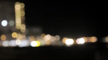 Pencerelerdeki fenerlerin ışıkları ve sütunlardaki fenerler ön odak noktasından normale dönüyor. Deniz kıyısında bulanık ışıklar.