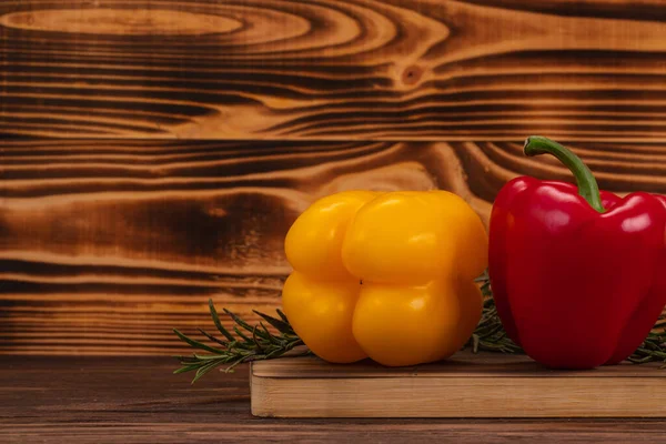 Close up of a yellow bell pepper and a red bell pepper on a wooden table. Fresh and organic bio vegetables