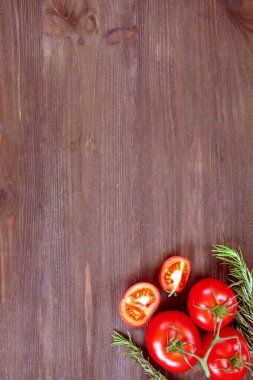 Taze sebzeler, kırmızı kiraz domatesleri ve ahşap arka planda biberiye dalı. Üst görünüm, metin için boşluk kopyala