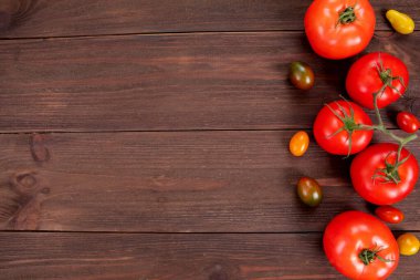 Farklı renklerde lezzetli kiraz domatesleri ve kopyalanmış ahşap yüzeyde taze domatesler. Sulu sebzeler, biyolojik yiyecekler.