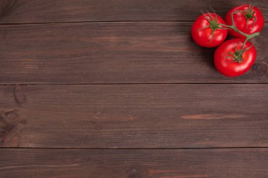 Kırsal ahşap zemin üzerinde üç olgun kırmızı domatesli bir dal ve fotokopi alanı. Taze sebzeler, üst manzara.