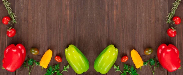 Various colorful vegetables like cherry tomatoes, bell peppers, mini peppers and parsley leaves on wooden background. Top view with copy space