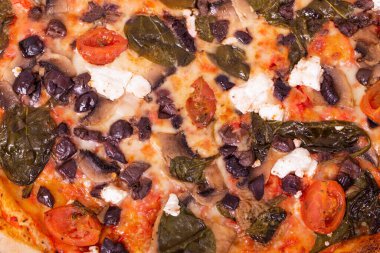 Mozarella, feta, vişneli domates, ıspanak, mantar ve kalamata zeytinli geleneksel lezzetli pizza, yakın görüş, makro fotoğraf.