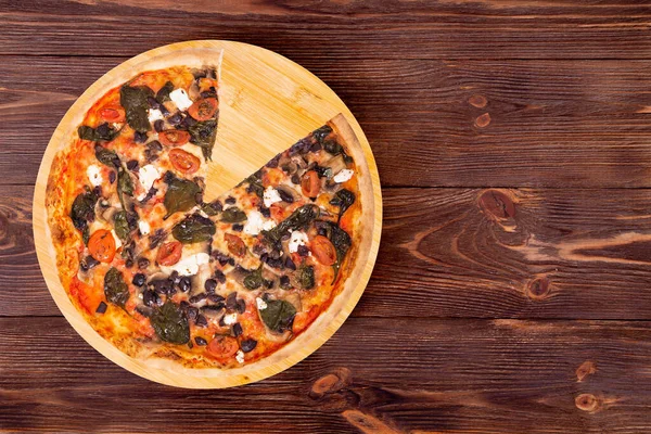 피자에는 토마토 시금치 모차렐라 올리브와 버섯이 있으며 원목적 배경에 접시에는 — 스톡 사진