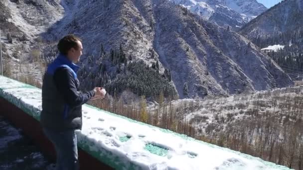 Guy sta facendo palle di neve e divertirsi in inverno paesaggio bellissime montagne in Almaty — Video Stock