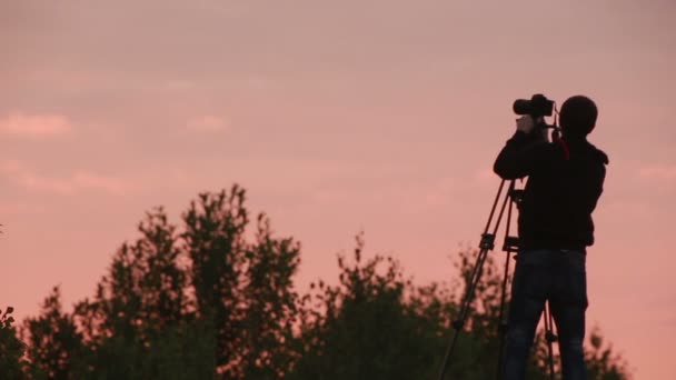 Kameraman fotografování západu slunce obloha — Stock video