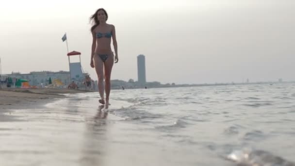 Linda joven hermosa chica con figura deportiva caminando en la playa de arena en verano vocación mar vacaciones viaje — Vídeo de stock