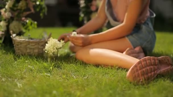 Joven europeo adolescente chica haciendo un arco floral sentado en esmeralda fresco hierba dolly cam — Vídeos de Stock