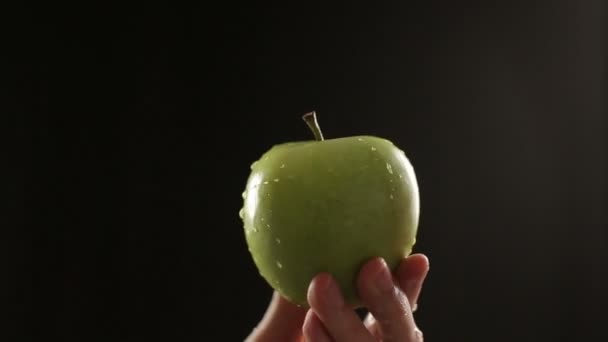 Dagg på grönt äpple isolerade i svart snodd håller i handen — Stockvideo
