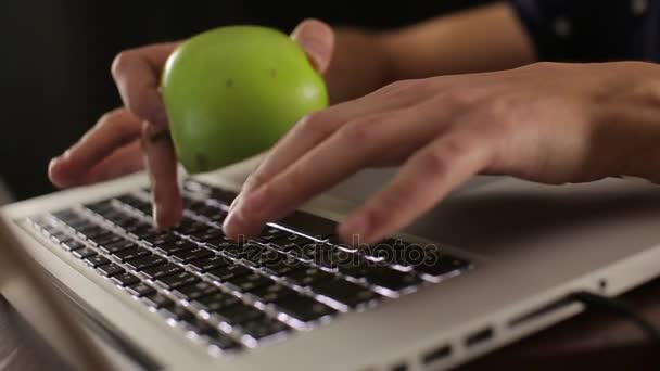 Mannelijke handen houden van groene appel en typen op toetsenbord laptop — Stockvideo