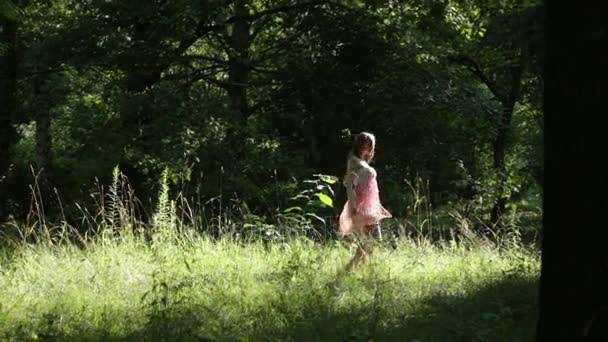 Симпатичная молодая девушка в мягком воздушном платье из кружева и улыбаясь на летней лесной лужайке — стоковое видео