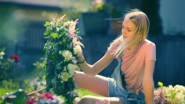 Letní slunečný lesklý dovolené vzpomínky - blonďatá usmívající se dívka dělat nabídka květinové kompozice z růžové a bílé květy — Stock video